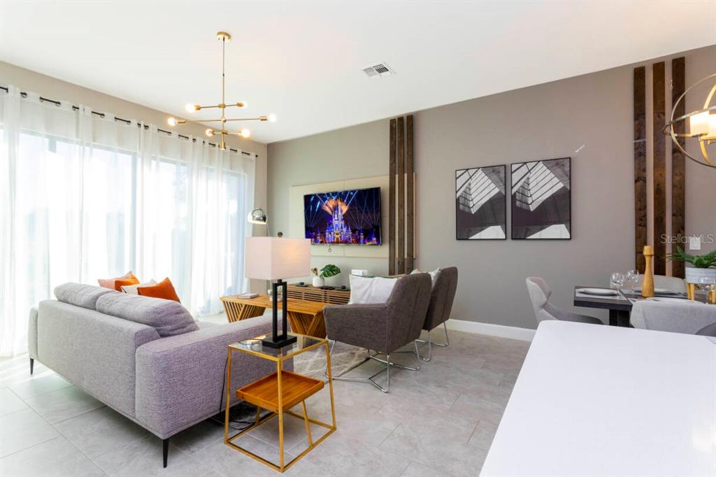 A modern living room features a gray sofa, two armchairs, a television, and dining area — 168 VILLA DOMANI CIRCLE, DAVENPORT, FL
