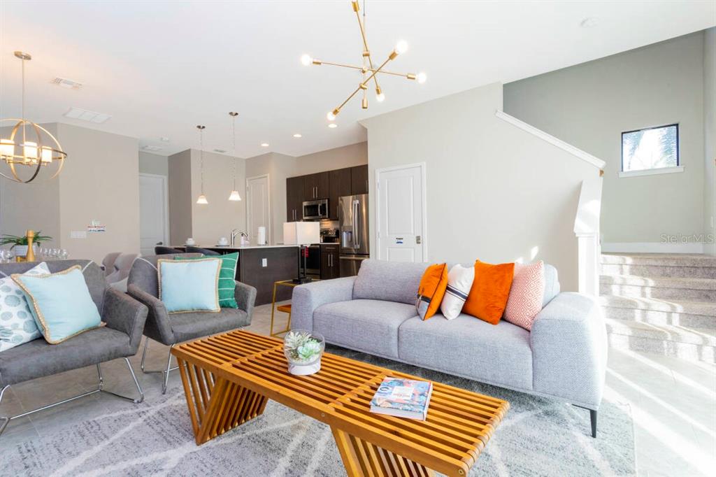 A living room with a grey sofa, two armchairs, and a wooden slatted coffee table — 168 VILLA DOMANI CIRCLE, DAVENPORT, FL