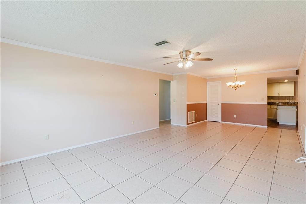 An open-concept living and dining area features light-colored floor tiles and two-toned wall paint — 1201 CARA DRIVE, LARGO, FL
