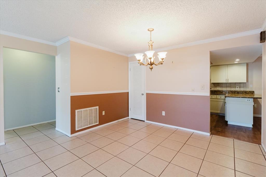 A dining room features tiled floors, two-toned walls, a chandelier, and an adjacent kitchen — 1201 CARA DRIVE, LARGO, FL