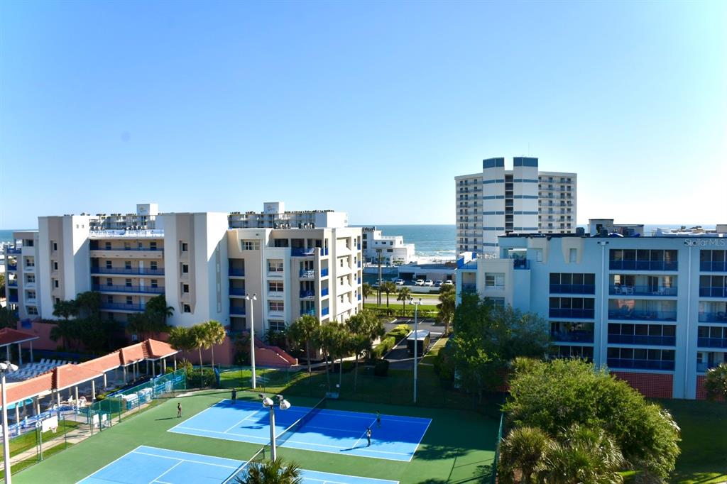 An elevated view of tennis courts in front of multi-story apartment buildings near the ocean — 5300 S ATLANTIC AVENUE UNIT 8-302, NEW SMYRNA BEACH, FL