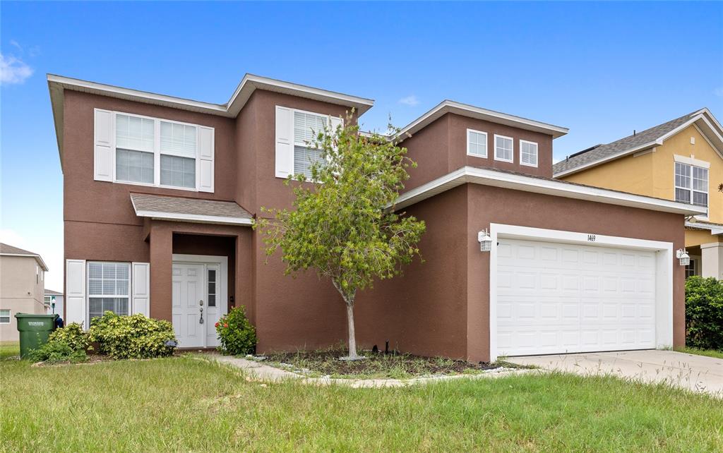 A two-story brown house with a white garage door, white shutters, and a small tree — 1469 SALISBURY DRIVE, WINTER HAVEN, FL