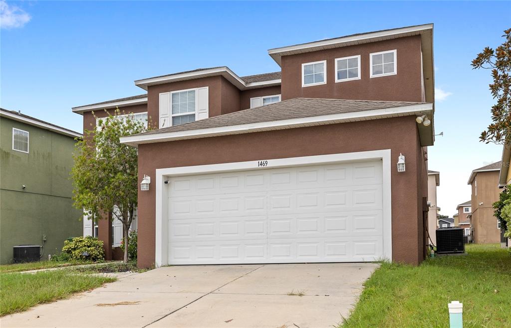 A two-story brown house with a white garage door and a concrete driveway — 1469 SALISBURY DRIVE, WINTER HAVEN, FL