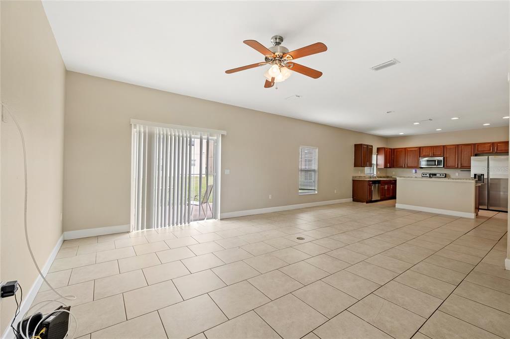 An open-concept living area with tile flooring, a ceiling fan, and an adjacent kitchen — 1469 SALISBURY DRIVE, WINTER HAVEN, FL