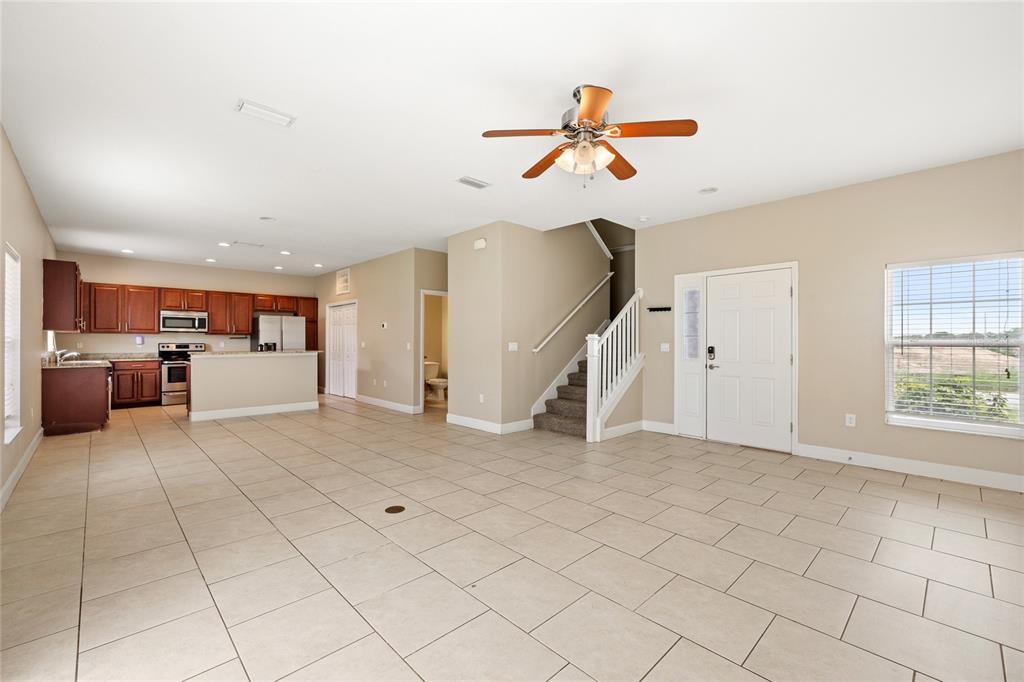 An open-concept living area features tile flooring, a kitchen with wood cabinets, and a staircase — 1469 SALISBURY DRIVE, WINTER HAVEN, FL