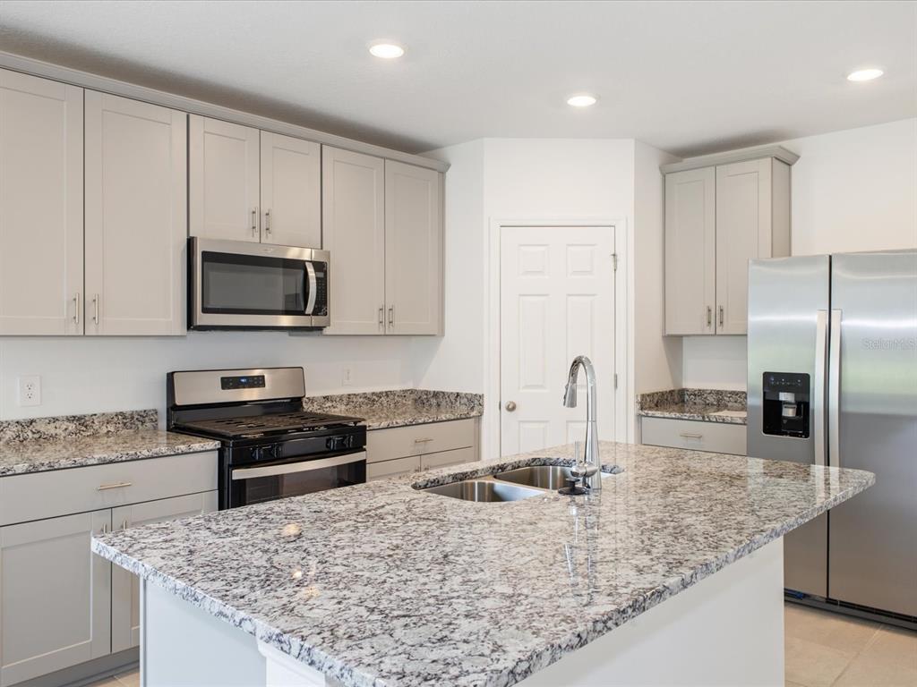 A kitchen with light gray cabinets, granite countertops, stainless steel appliances, and a central island — 4542 EAGLE PERCH COURT, ST CLOUD, FL
