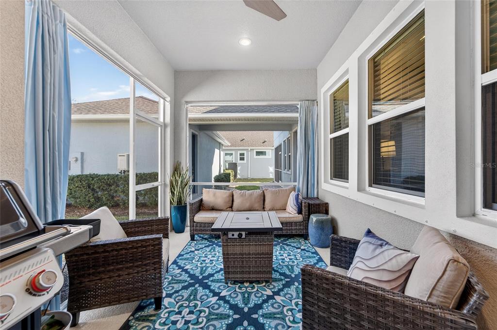 A screened-in patio features wicker furniture, a fire pit table, and a blue patterned rug — 707 WINTERSIDE DRIVE, APOLLO BEACH, FL
