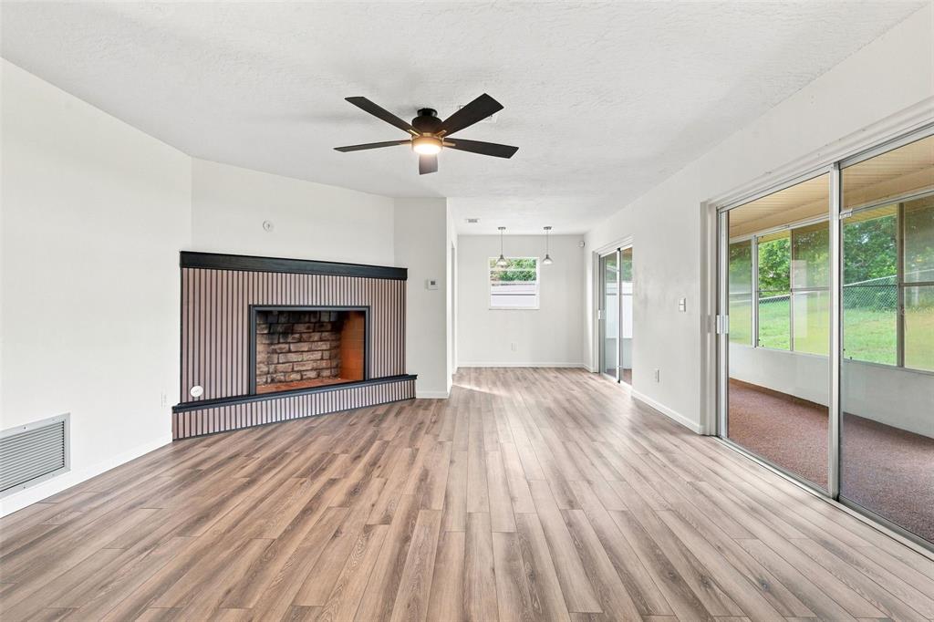 A dining area features light wood-look flooring, two pendant lights, a central window, and sliding doors — 1441 NE OLD MILL DRIVE, DELTONA, FL
