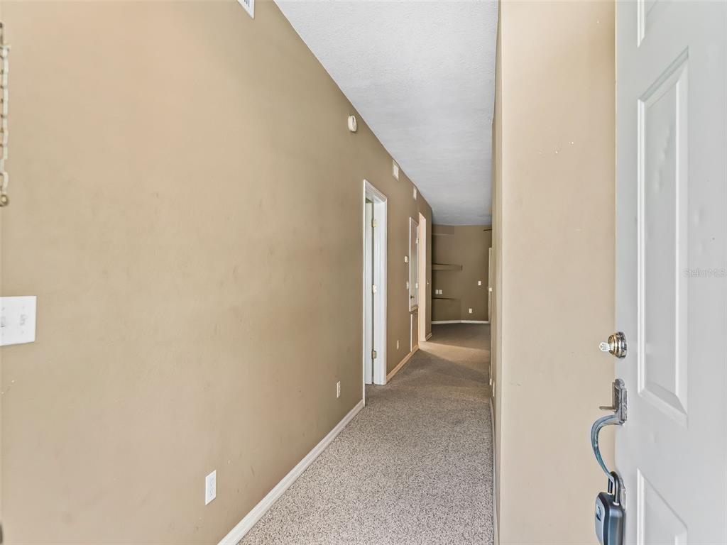 A carpeted hallway leads from an open door toward a room with built-in shelves — 231 NE 28TH AVENUE UNIT 309, OCALA, FL