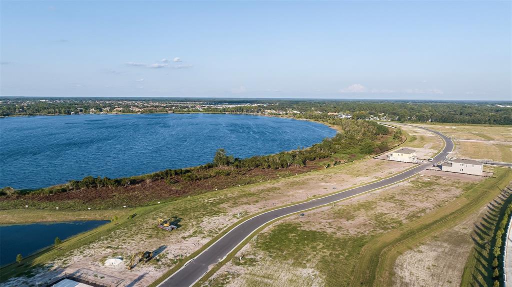 An aerial view shows a large lake bordered by a new residential development under construction — 19341 LOCHSIDE LANE, MOUNT DORA, FL