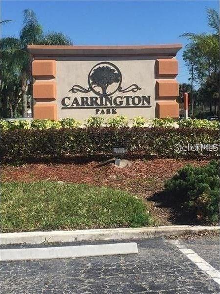 A beige monument sign for Carrington Park stands in front of landscaping and palm trees — 452 BANYON TREE CIRCLE UNIT 200, MAITLAND, FL