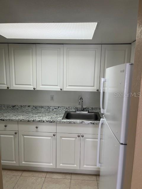 A kitchen features white cabinets, granite countertops, a stainless steel sink, and a white refrigerator — 452 BANYON TREE CIRCLE UNIT 200, MAITLAND, FL
