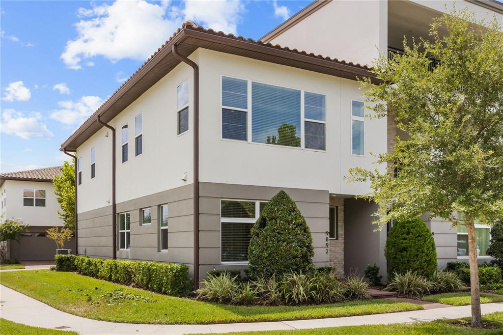 A two-story residential building with a stucco exterior, brown trim, and a tiled roof — 9892 BUCKLOW HILL DRIVE, ORLANDO, FL