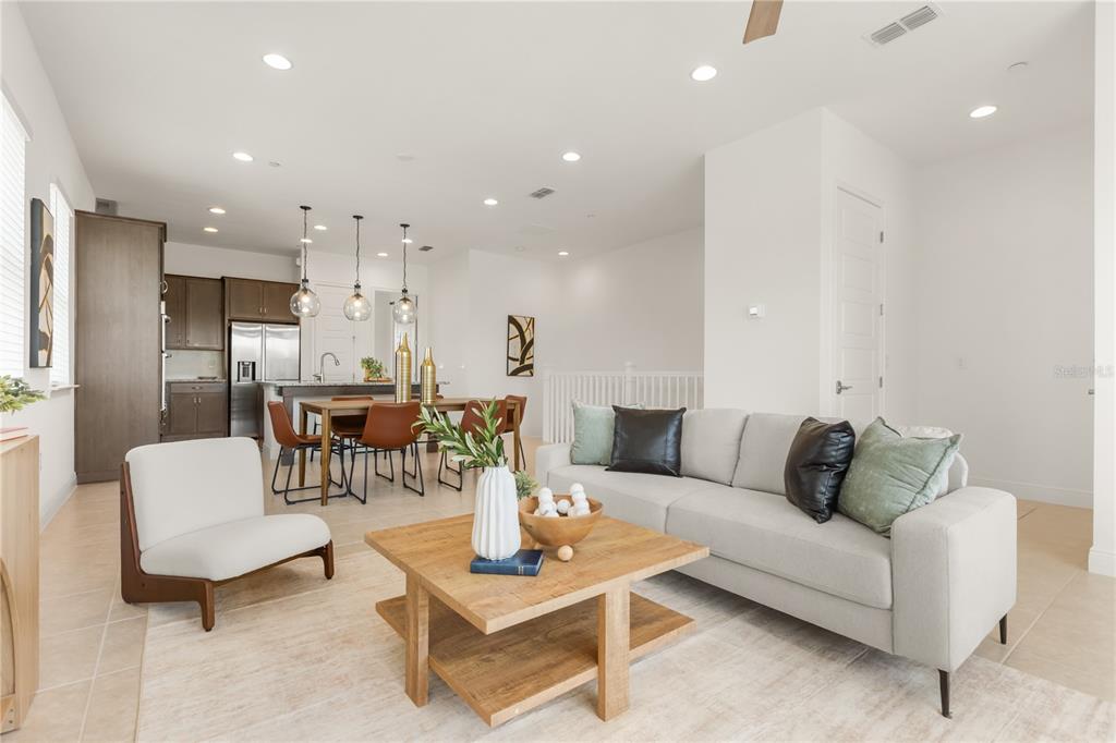 A bright, open-concept living room and dining area featuring light tile floors and modern furnishings — 9892 BUCKLOW HILL DRIVE, ORLANDO, FL