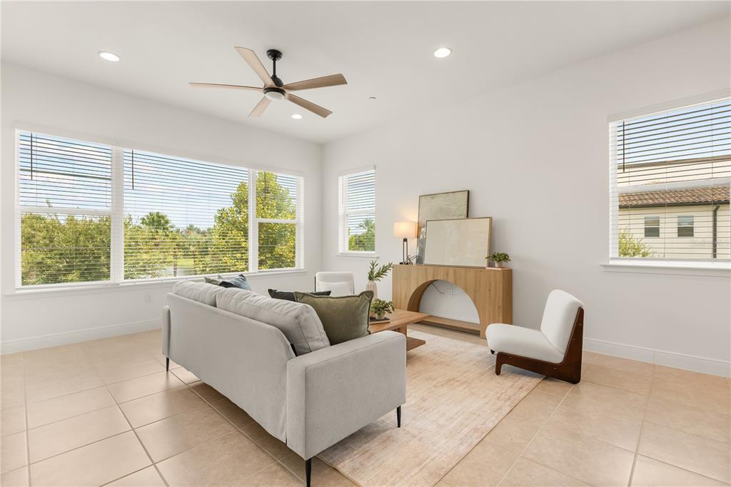 A bright living room features a gray sofa, a wood console table, and large windows — 9892 BUCKLOW HILL DRIVE, ORLANDO, FL