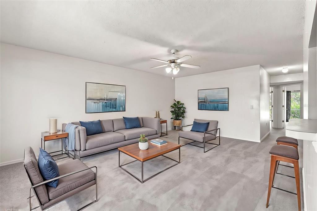 A living room with gray carpet, a sofa, two armchairs, and a wooden coffee table — 22278 VICK STREET UNIT A101, PORT CHARLOTTE, FL