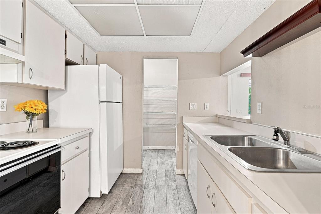 A kitchen features white cabinets, a white refrigerator, a double sink, and light wood-look flooring — 22278 VICK STREET UNIT A101, PORT CHARLOTTE, FL