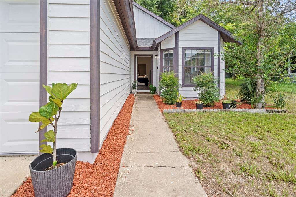 A concrete walkway leads to the front entrance of a house with white horizontal siding — 555 SWALLOW COURT, APOPKA, FL