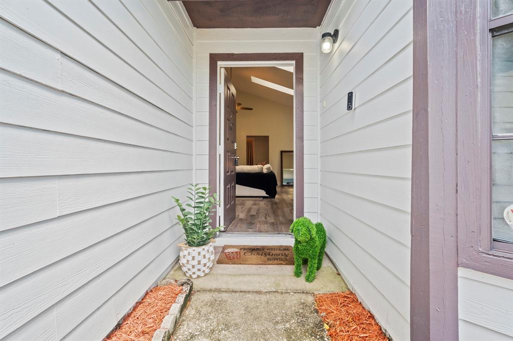 The exterior entryway features white horizontal siding, a brown door, and a decorative topiary dog — 555 SWALLOW COURT, APOPKA, FL