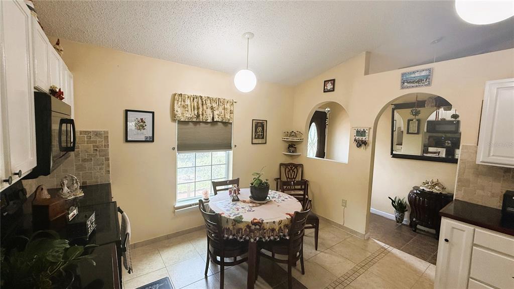 A kitchen with a dining area, tile floors, white cabinets, and a round table — 140 PERSIMMON DRIVE, PALM COAST, FL