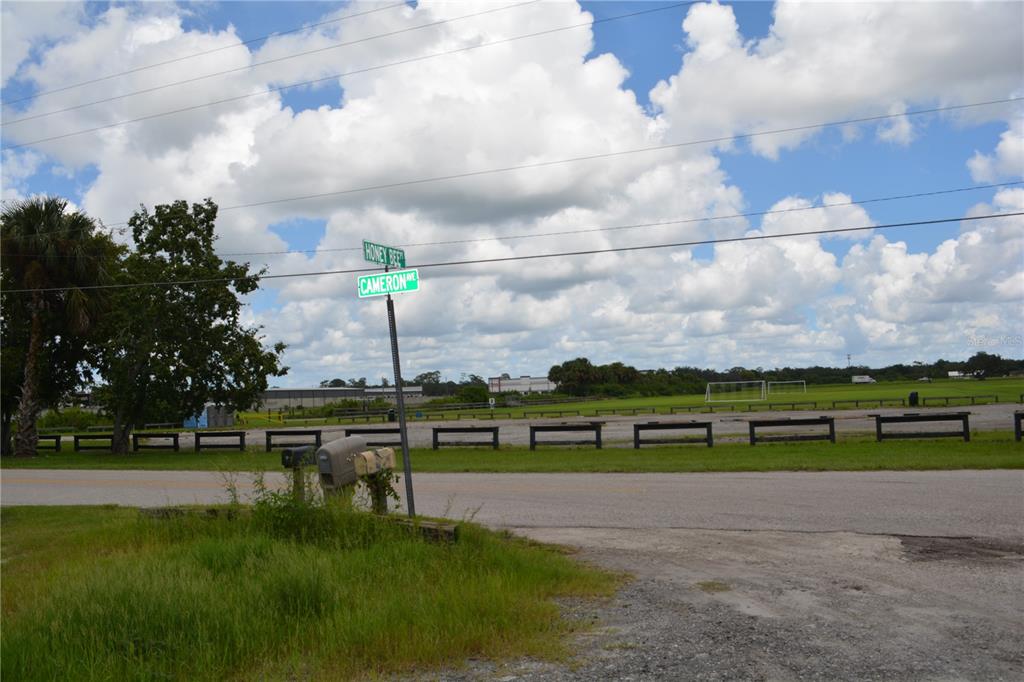 A street sign at the intersection of Honey Bee and Cameron Avenue overlooks a grassy field — 4045 HONEY BEE PT ROAD, SANFORD, FL