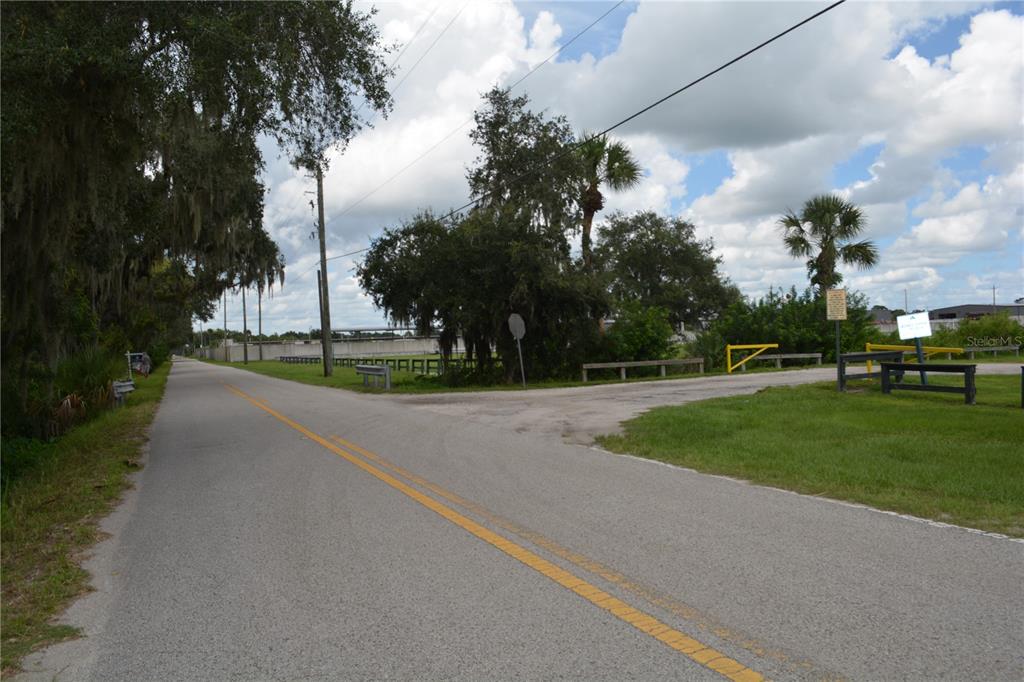 A paved road with a yellow center line leads toward a gated entrance and trees — 4045 HONEY BEE PT ROAD, SANFORD, FL