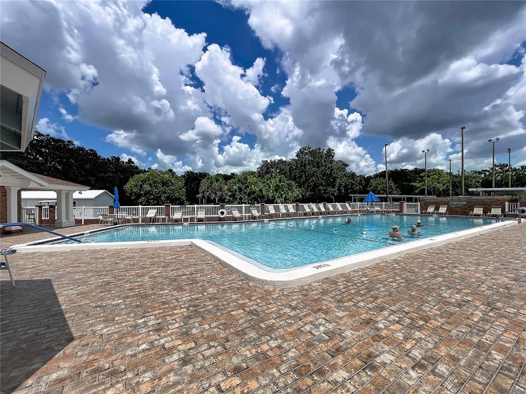 A rectangular swimming pool with a brick deck is surrounded by a white fence — 4983 PLEASANT HOLLOW TRAIL, LAKELAND, FL