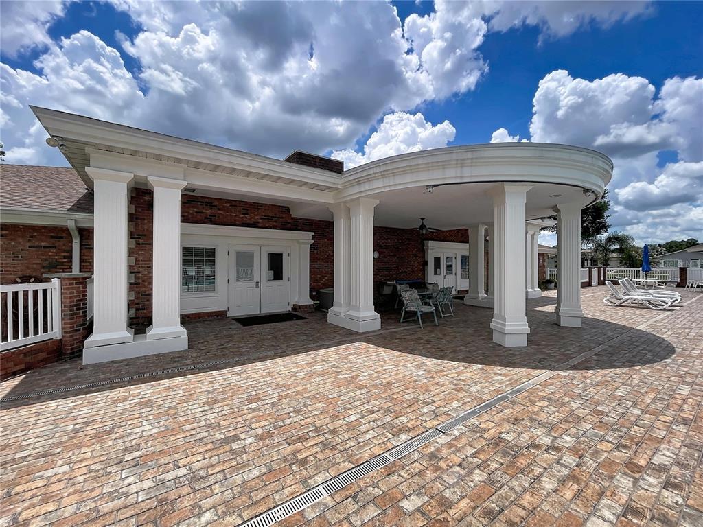 A brick patio features a covered seating area with white columns under a blue sky — 4983 PLEASANT HOLLOW TRAIL, LAKELAND, FL