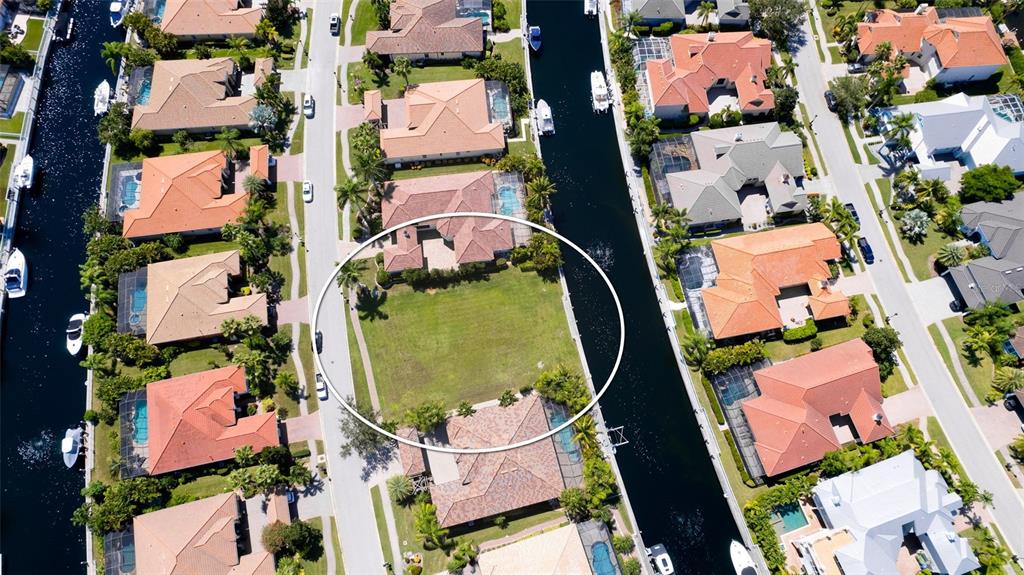 An aerial view shows a vacant residential lot situated between two houses along a canal — 540 MAST DRIVE, BRADENTON, FL