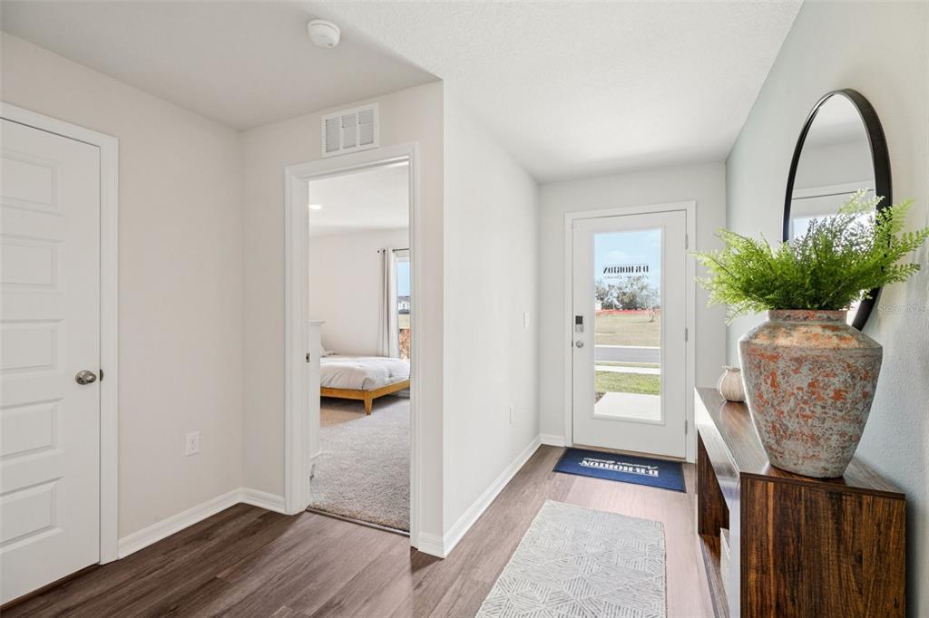 An entryway features wood-look flooring, a white front door, and a view into a bedroom — 4410 BLACKWELL AVENUE, LAKE WALES, FL