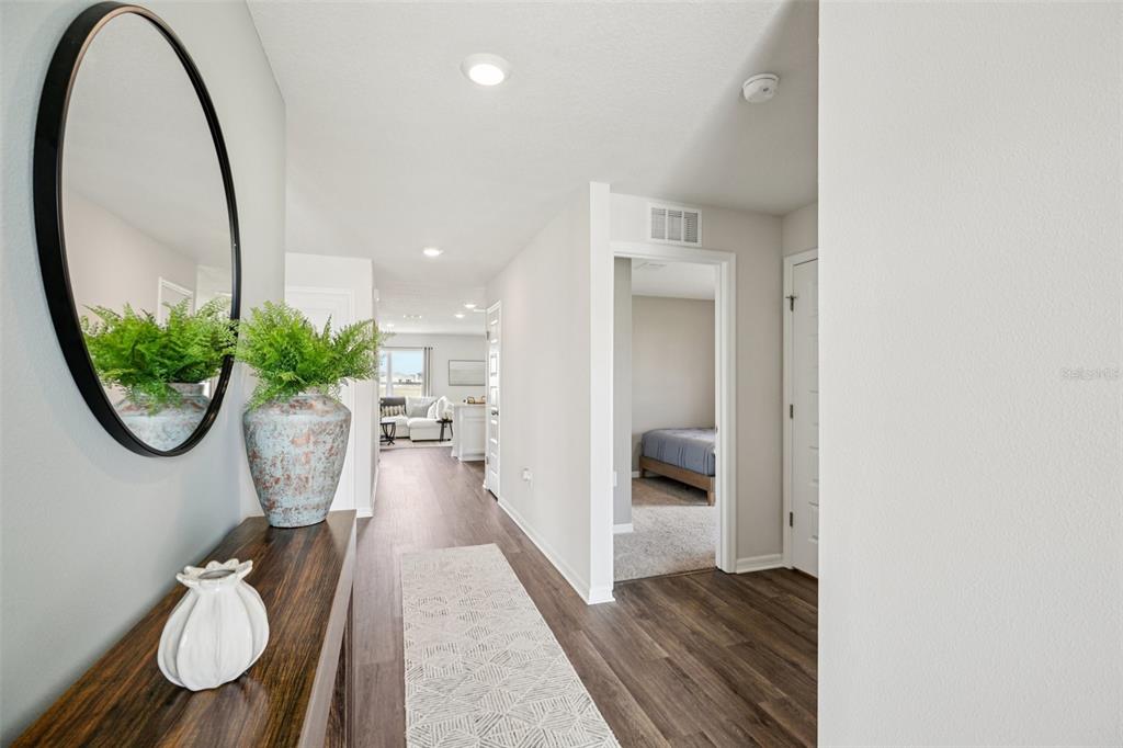 A hallway with wood-look flooring leads past a bedroom toward a bright living area — 4410 BLACKWELL AVENUE, LAKE WALES, FL