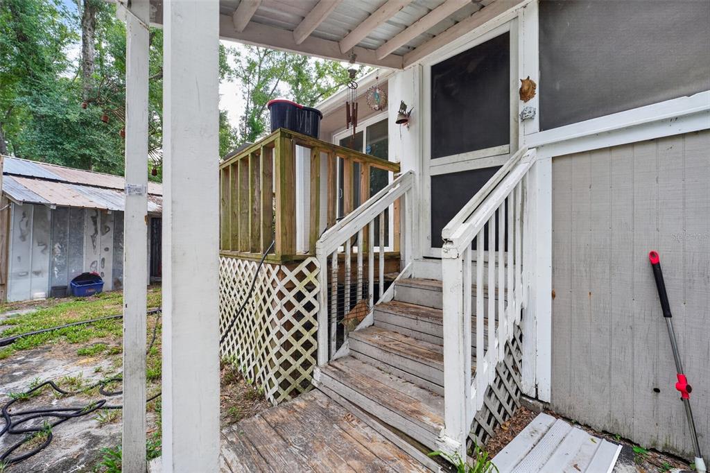A wooden staircase leads to a screened door and a small deck with lattice skirting — 4389 288TH TERRACE, BRANFORD, FL