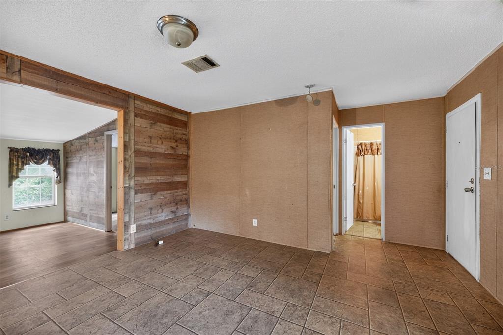An interior view of a room with tile flooring, wood-paneled walls, and a doorway to a bathroom — 4389 288TH TERRACE, BRANFORD, FL
