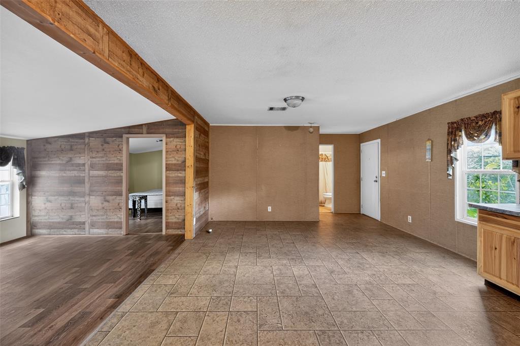 An interior view shows a living area with tile flooring, wood-paneled walls, and a doorway — 4389 288TH TERRACE, BRANFORD, FL