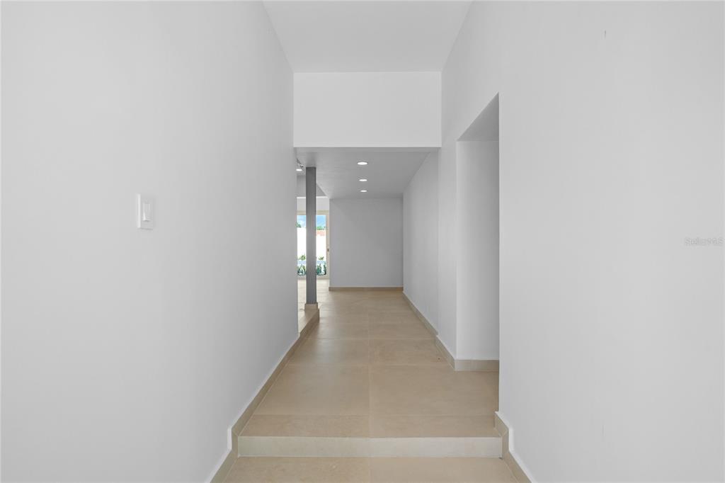 A hallway with light-colored tile flooring leads toward a doorway with a view outside — E 10 CALLE MADRE PERLA, DORADO, PR