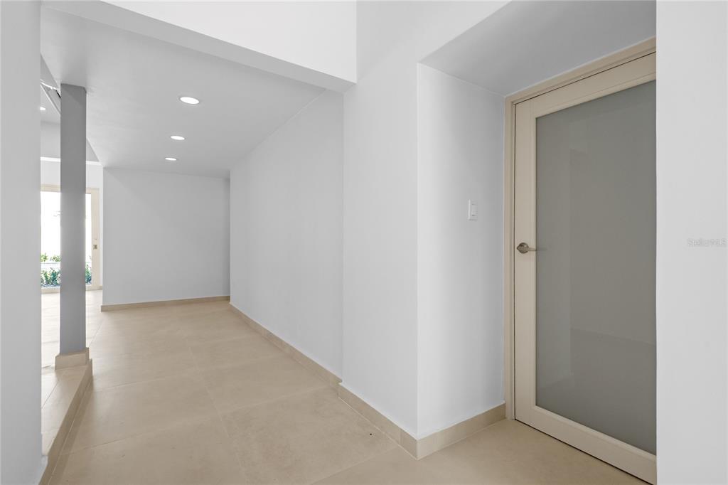 A hallway with light-colored tile flooring, white walls, recessed lighting, and a frosted glass door — E 10 CALLE MADRE PERLA, DORADO, PR