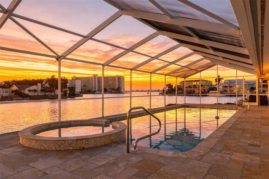 A screened-in pool and hot tub overlook a waterfront view at sunset — 5921 SEABIRD DRIVE S, GULFPORT, FL