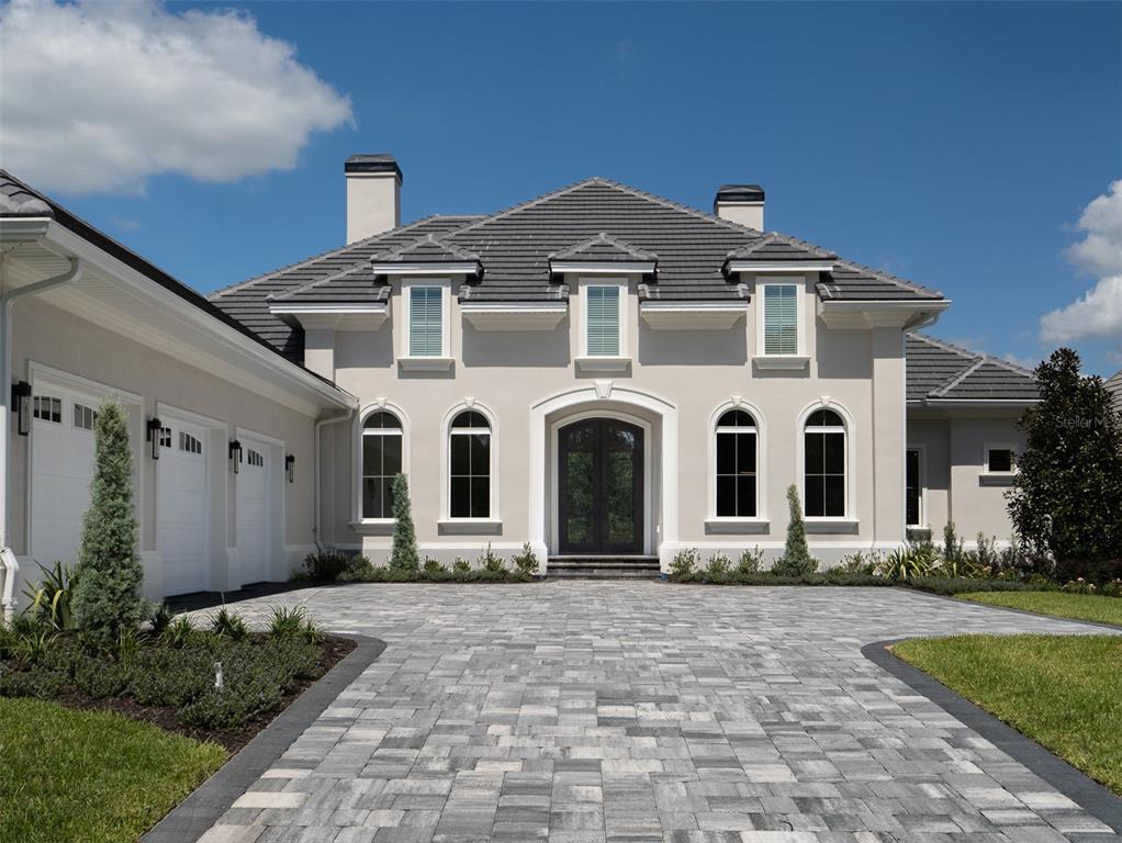 A two-story house with a gray tiled roof, beige stucco exterior, and a paved driveway — 7647 NW 33RD PLACE, OCALA, FL