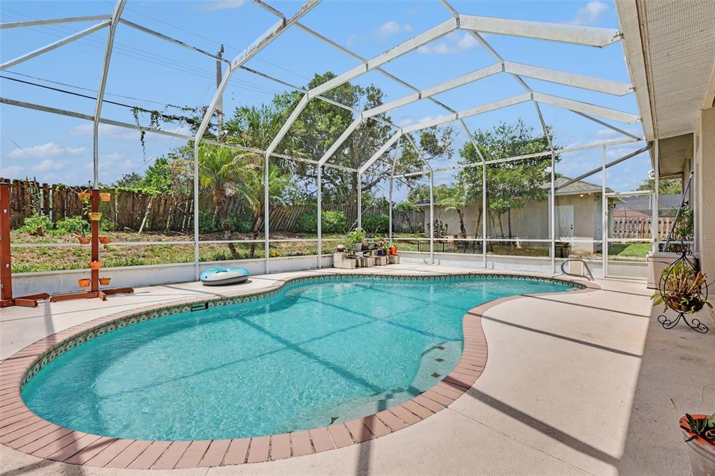 A swimming pool with a brick-paver border is enclosed by a white metal screen cage — 3724 S RIDGE CIRCLE, TITUSVILLE, FL