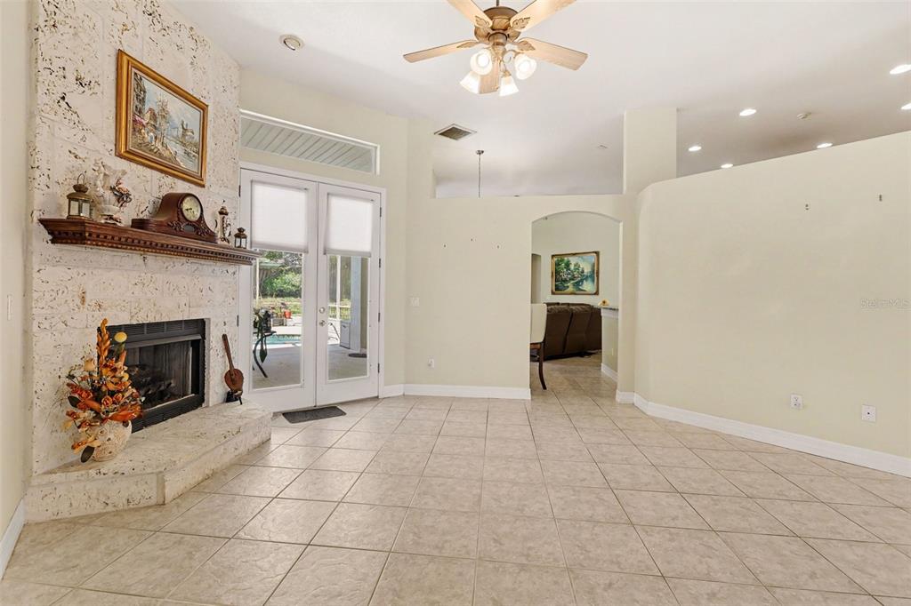 A living room features a stone fireplace, tile flooring, a ceiling fan, and glass doors — 3724 S RIDGE CIRCLE, TITUSVILLE, FL