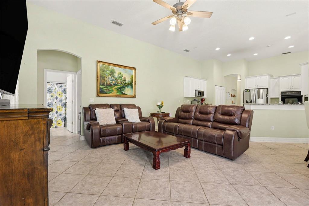 A living room with tile floors, brown leather furniture, and an open kitchen in the background — 3724 S RIDGE CIRCLE, TITUSVILLE, FL