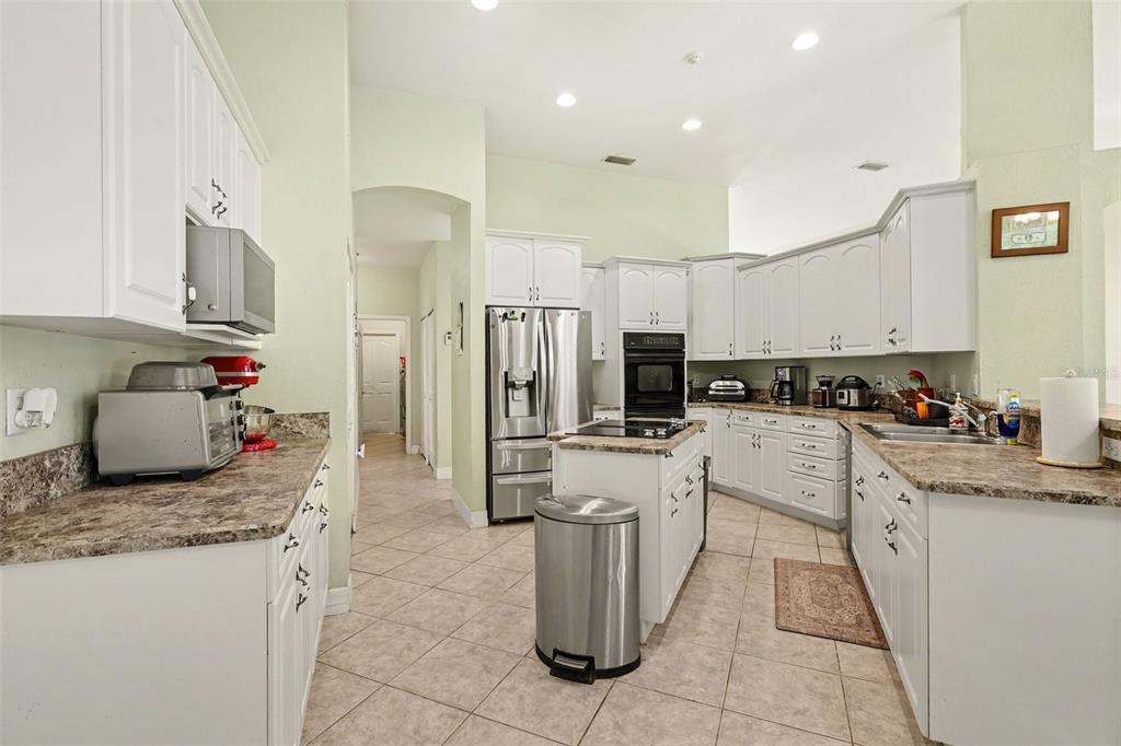 A kitchen with white cabinets, stainless steel appliances, a center island, and tile flooring — 3724 S RIDGE CIRCLE, TITUSVILLE, FL