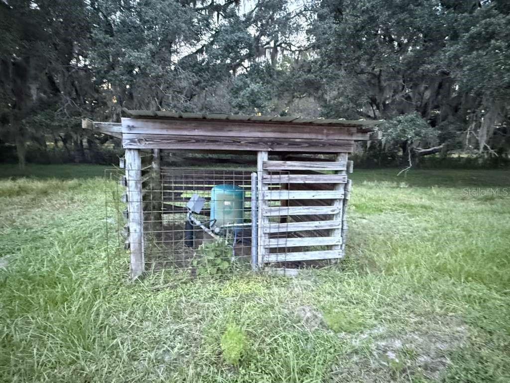 A small, wooden-framed well house with a metal roof stands in a grassy field — 27900 BAYHEAD ROAD, DADE CITY, FL