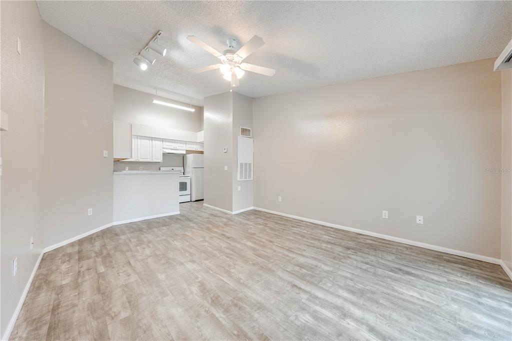 An open-concept living area with light wood-look flooring, a ceiling fan, and an adjacent kitchen — 2210 YANKEE PLACE UNIT 334, ORLANDO, FL
