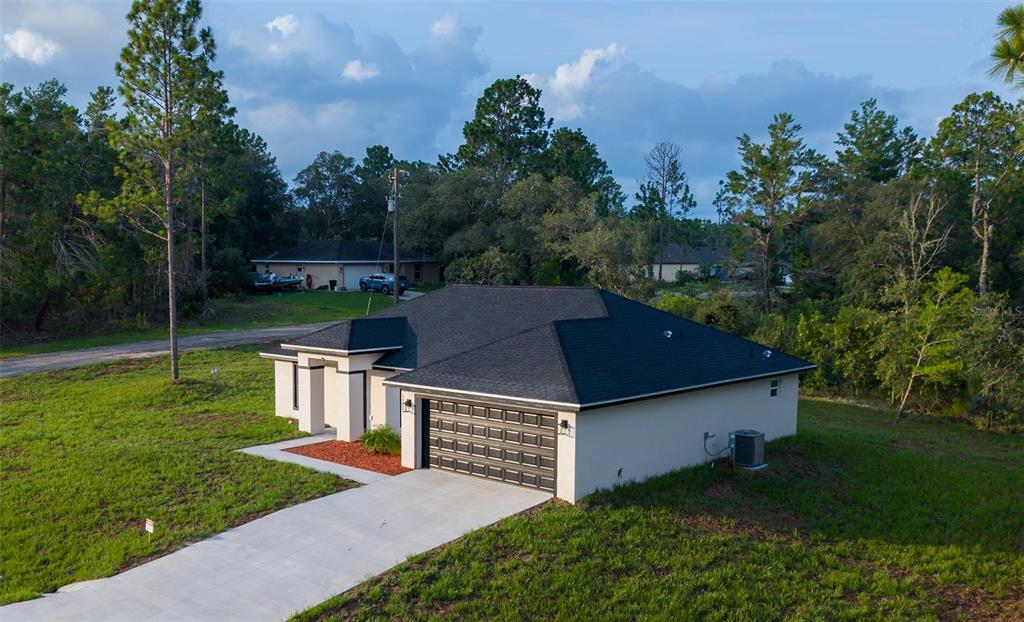 An aerial view of a single-story house with a dark roof and a concrete driveway — 2902 W EDISON PLACE, DUNNELLON, FL