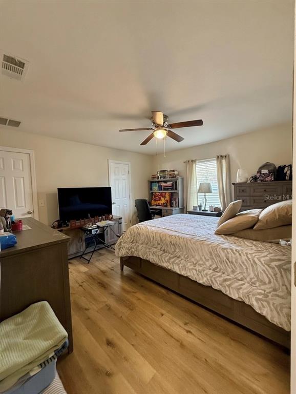 A bedroom features light wood flooring, a ceiling fan, a bed, and a television stand — 313 OAK STREET, AUBURNDALE, FL
