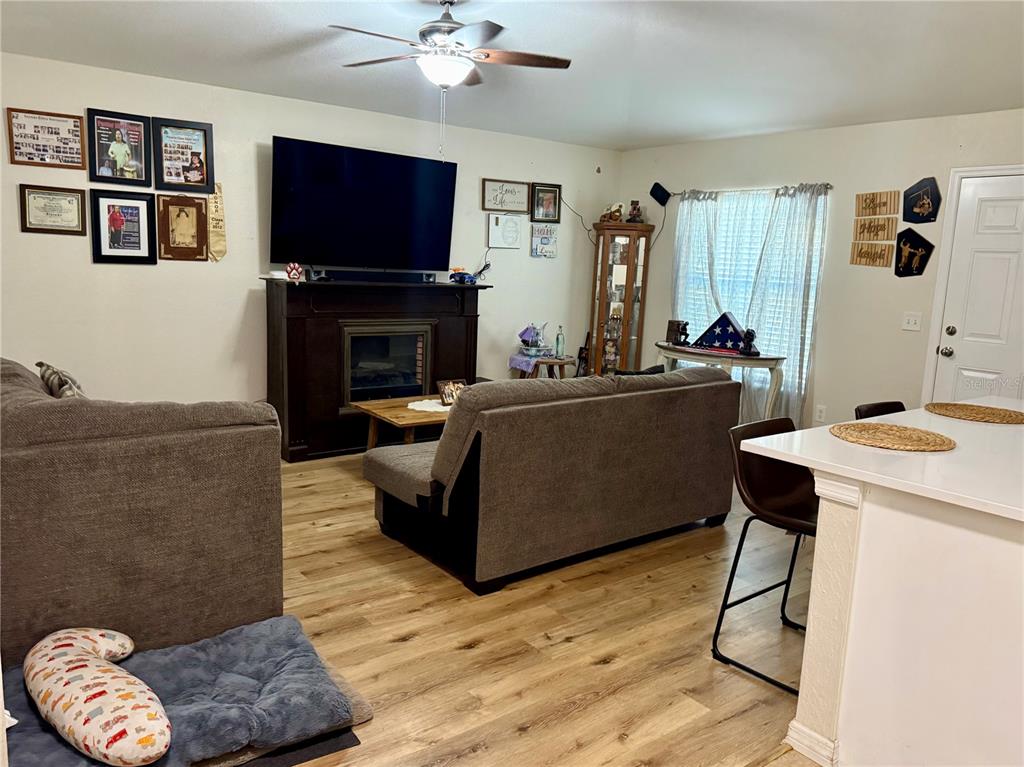 A living room features a fireplace, a large television, wood-look flooring, and a sofa — 313 OAK STREET, AUBURNDALE, FL