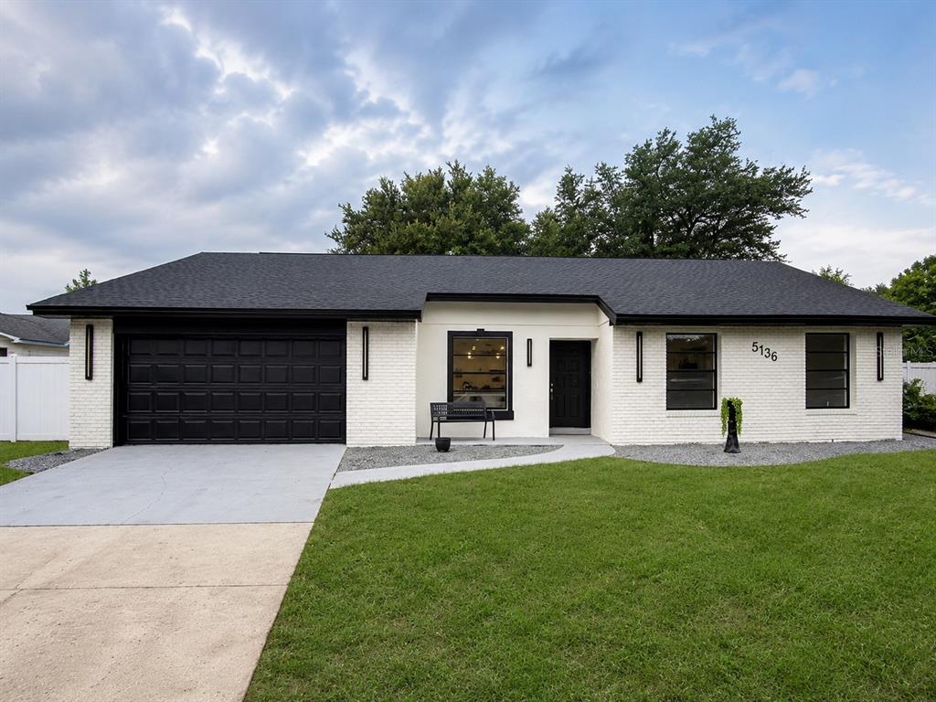 A single-story house with white brick walls, a black roof, and a black garage door — 5136 NADINE STREET, ORLANDO, FL