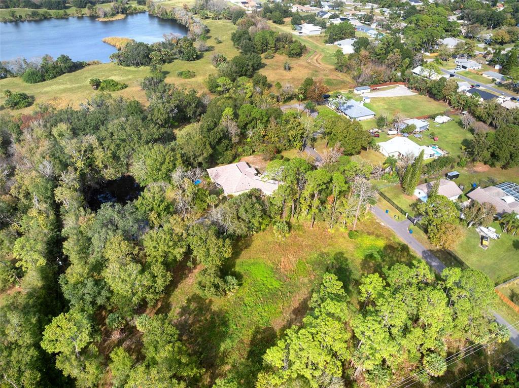 An aerial view shows a house surrounded by trees, a large lawn, and a lake — PINEDALE ROAD, EDGEWATER, FL