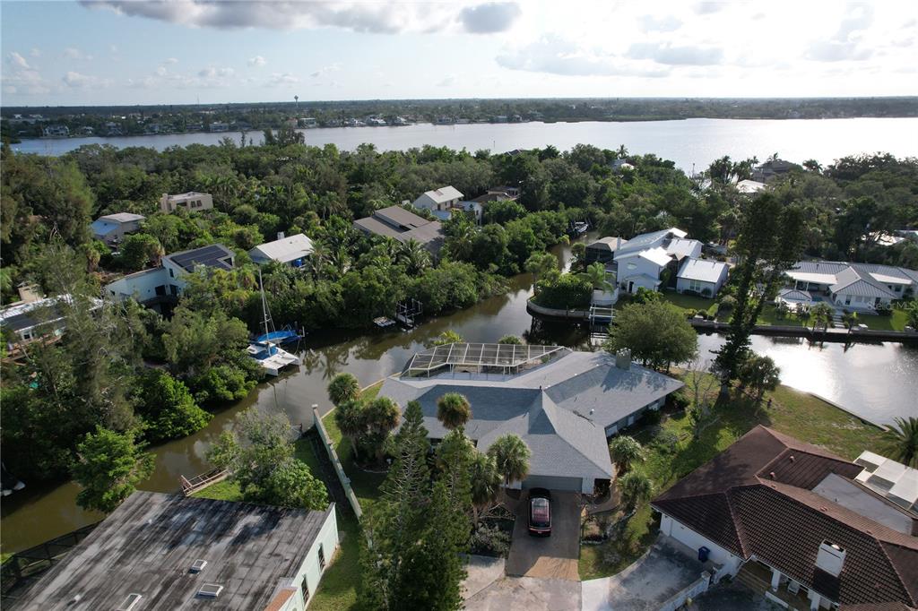 An aerial view of a waterfront house with a pool cage and a boat dock — 6937 MIDNIGHT PASS ROAD, SARASOTA, FL